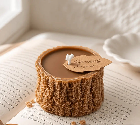 Vela rústica artesanal con forma de tronco de madera, con etiqueta "Especially for you", sobre un libro abierto, creando un ambiente acogedor.
